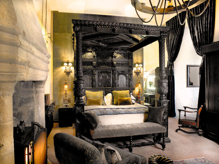 The Earl of Bothwell bedchamber, with a carved oak four-poster hung with dark curtains beside a stone chimney breast, Borthwick Castle