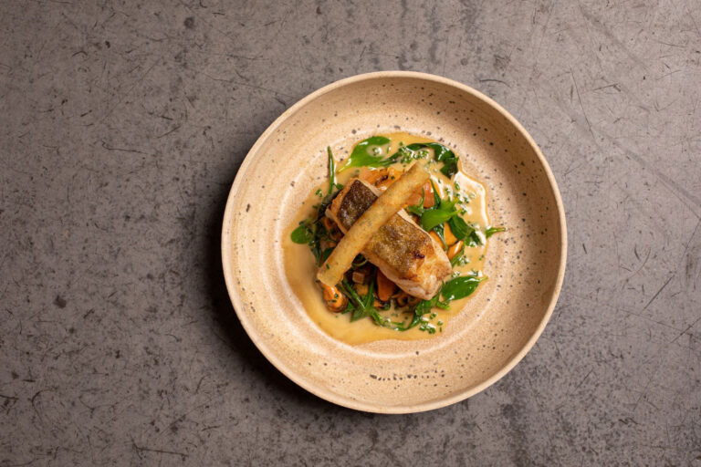 A plated fish course with greens and sauce in a speckled bowl, seen from above, Borthwick Castle