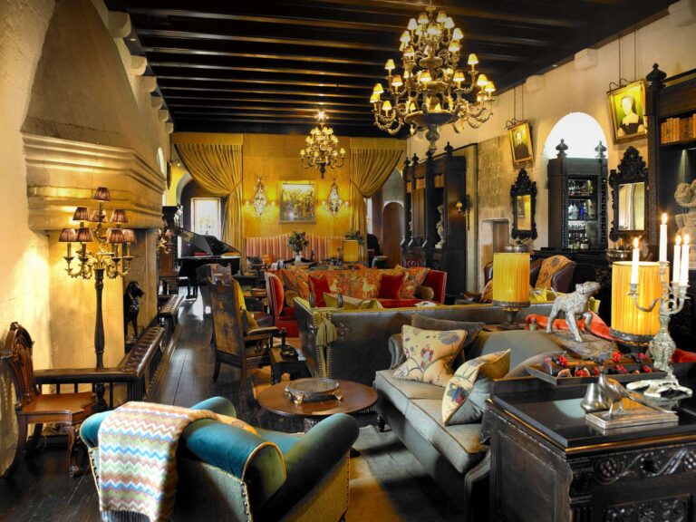 The State Room, with beamed ceiling, chandeliers, deep sofas and a stone hooded fireplace, Borthwick Castle