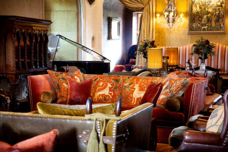 Velvet sofas and patterned cushions in the State Room, with the grand piano behind, Borthwick Castle