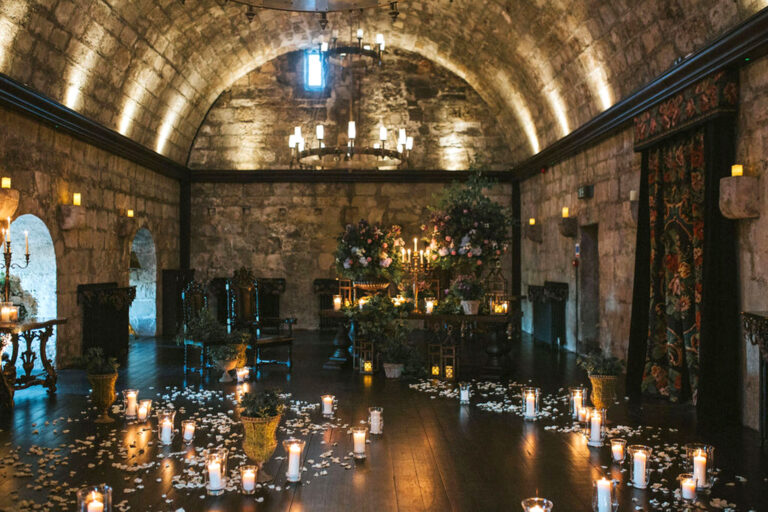 The Garrison's barrel-vaulted room lit by candles and scattered with petals, with flowers along the walls, Borthwick Castle
