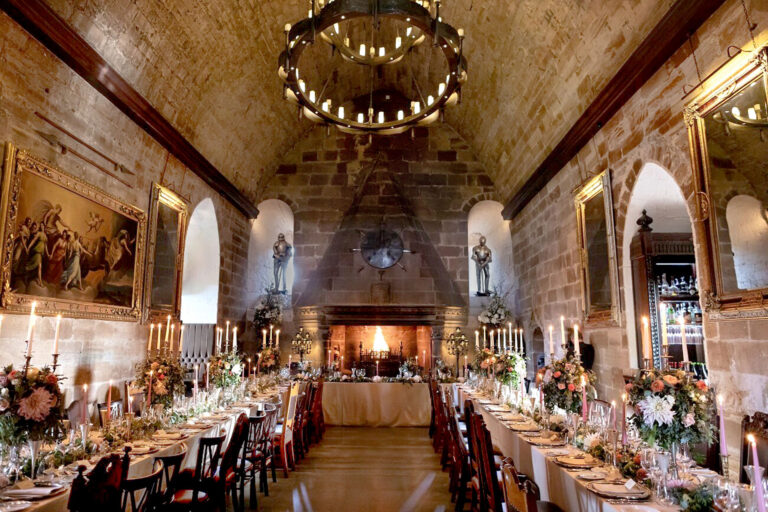 Two long tables running the length of the Great Hall towards a top table set before the hooded fireplace, Borthwick Castle