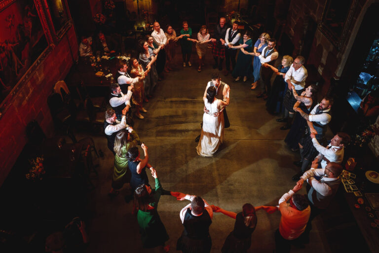Guests forming a ring around the couple's first dance in the Great Hall, seen from the gallery above, Borthwick Castle