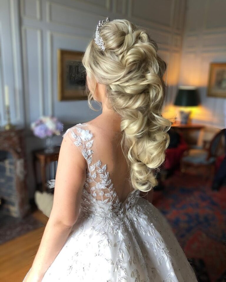 Cascading curls pinned high, set against gilt-framed portraits, Botias