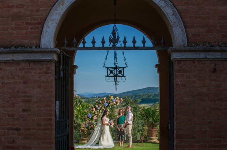 Couple at the altar seen through a brick archway, with a lake view beyond, Bottega dei Fiori by Ezio De Angelis