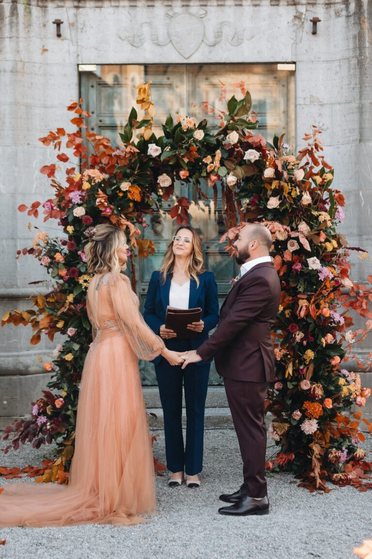 Couple and celebrant beneath an arch of autumn flowers, Bottega dei Fiori by Ezio De Angelis