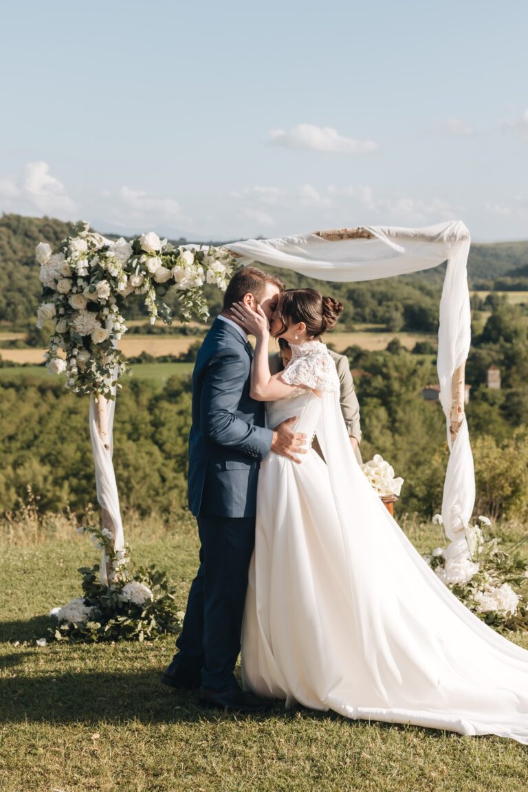 Couple kissing beneath a draped floral arch on a hillside, Bottega dei Fiori by Ezio De Angelis