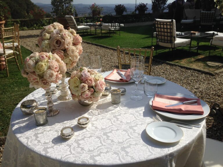 Round table with rose centrepieces and pink napkins in a garden, Bottega dei Fiori by Ezio De Angelis