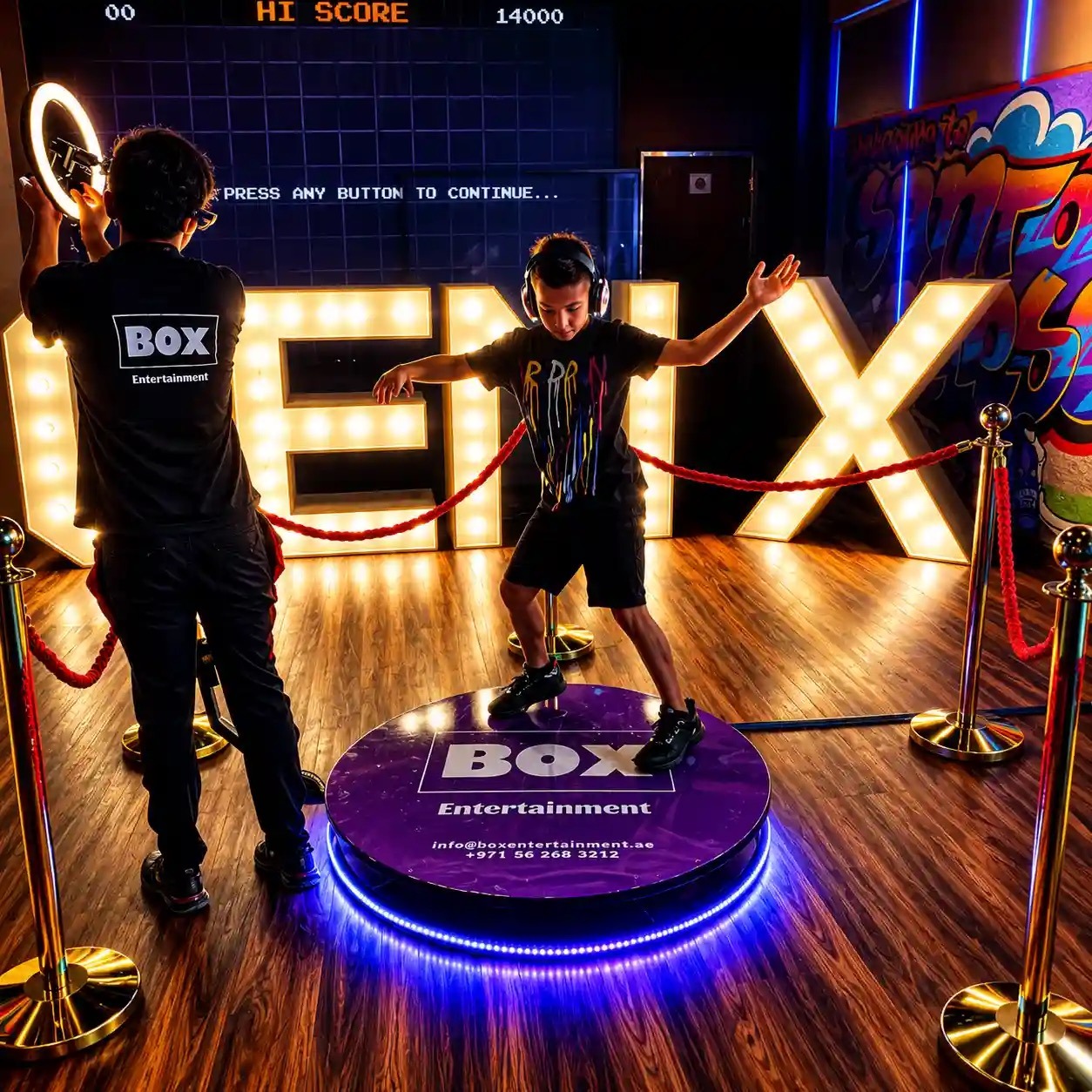 A guest poses on a branded 360 degree photo platform in front of lit marquee letters, Box Entertainment