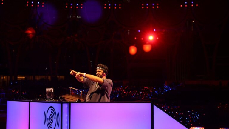 A DJ plays from a lit stage under red and blue lighting, Box Entertainment