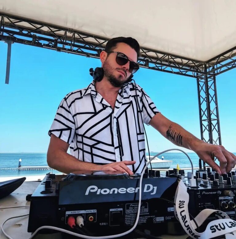 A DJ at a beachfront set under a truss canopy, Box Entertainment