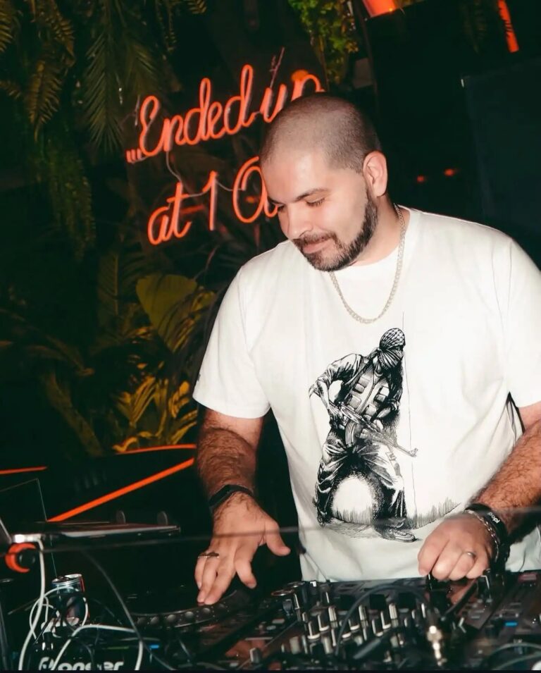A DJ at the decks in front of a neon sign, Box Entertainment