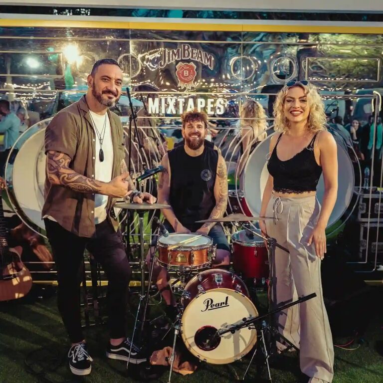 A live trio with a drum kit and guitars outdoors, Box Entertainment