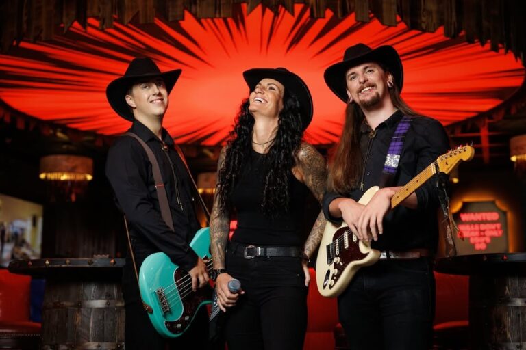 A three-piece band in black and hats, posed at a bar, Box Entertainment