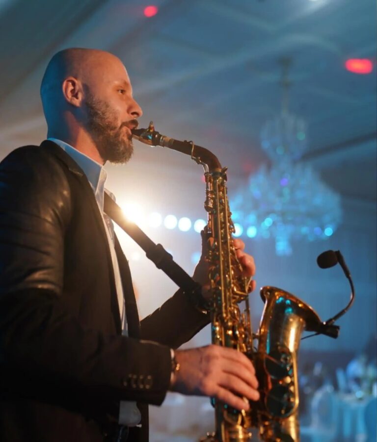 A saxophonist performing in a room lit with chandeliers, Box Entertainment