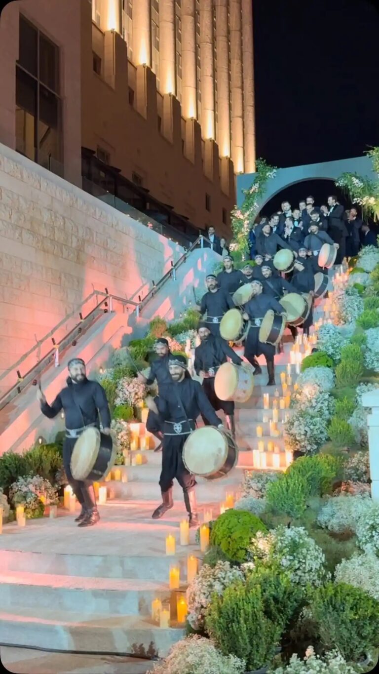 A troupe with drums coming down an illuminated staircase, Box Entertainment