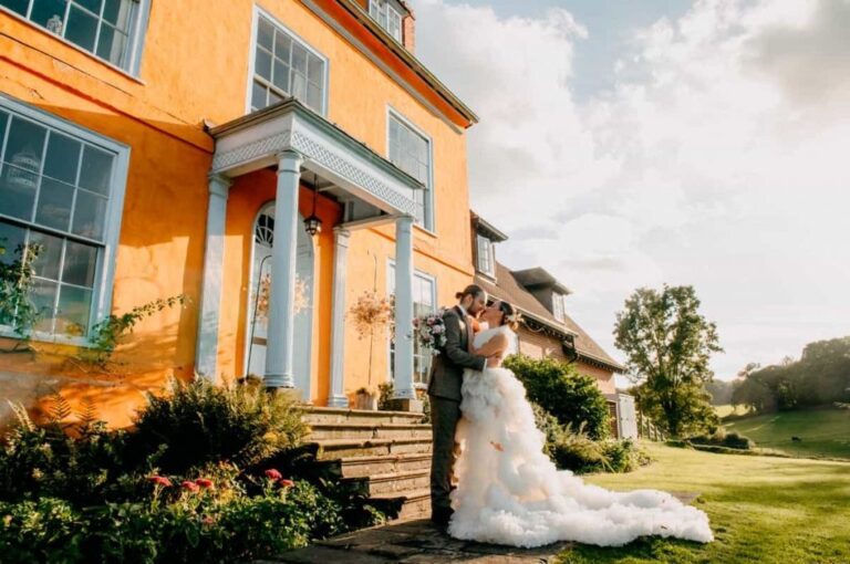 The ochre-rendered country house, a bride in tulle on the lawn in golden light, Briery Hill House