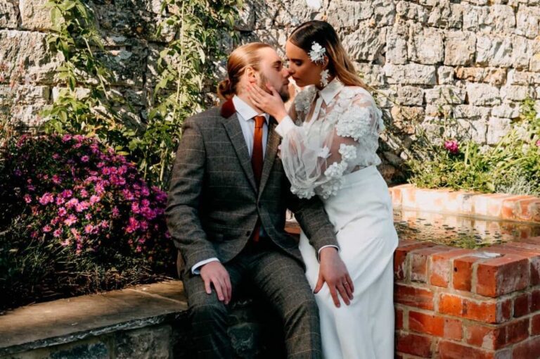 The couple seated against a flowering brick garden wall, Briery Hill House
