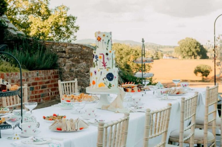 An outdoor reception table with a tiered cake and a sweeping countryside view, Briery Hill House
