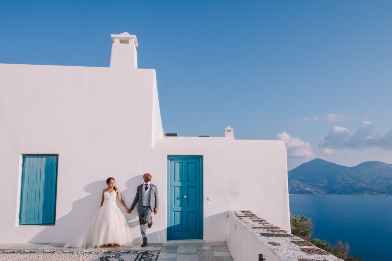 Couple walking by whitewashed houses with sea views, Milos, Bright Blue Wedding And Events