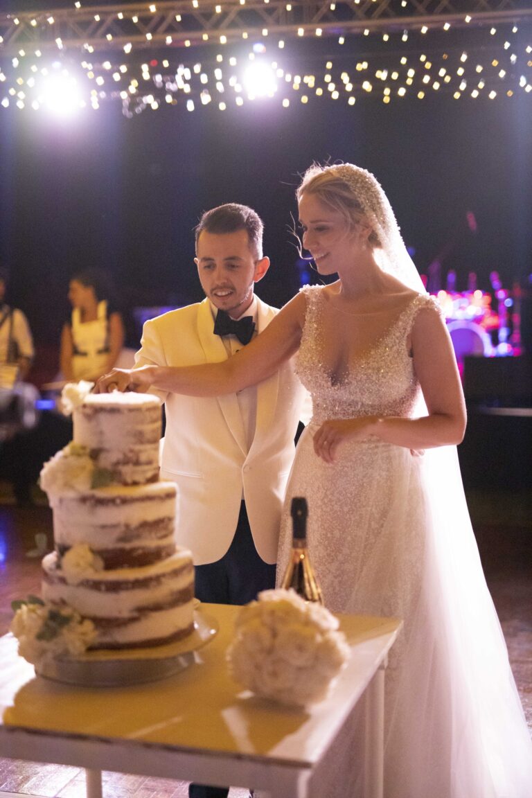 Couple cutting a naked wedding cake under festoon lights, Bright Blue Wedding And Events