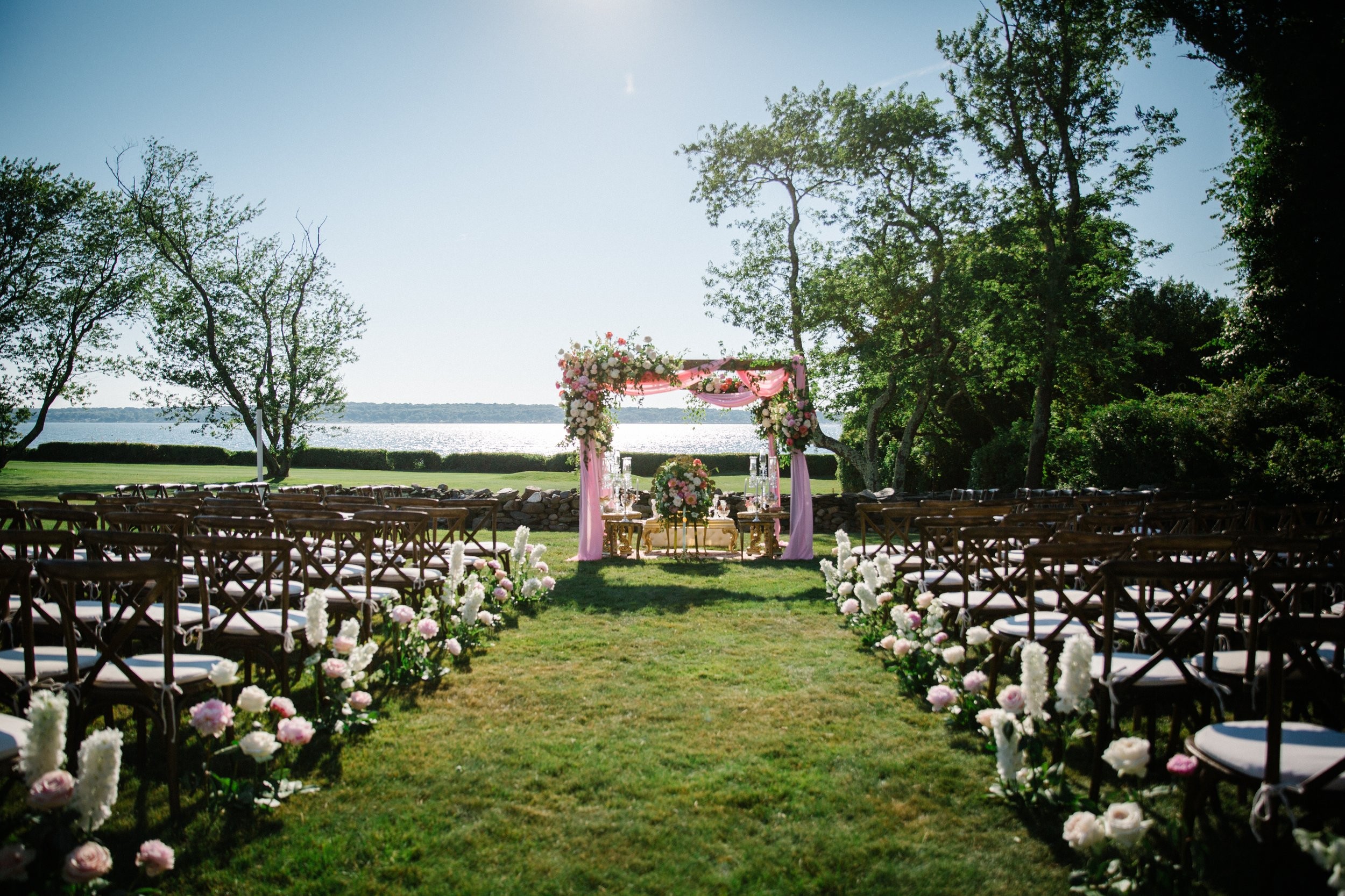 Ceremony lawn with cross-back chairs and flower-lined aisle overlooking the water, Newport, Brilliant Event Planning