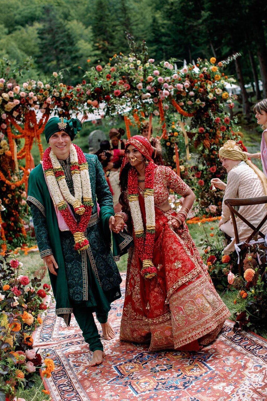 A couple walking through a marigold-draped mandap at an Indian fusion wedding
