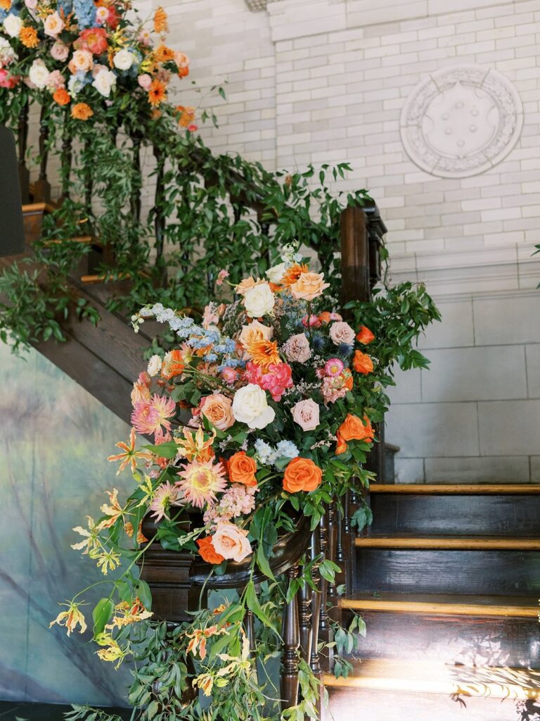 Staircase garlanded in orange and pink flowers, Brooklyn, Brilliant Event Planning