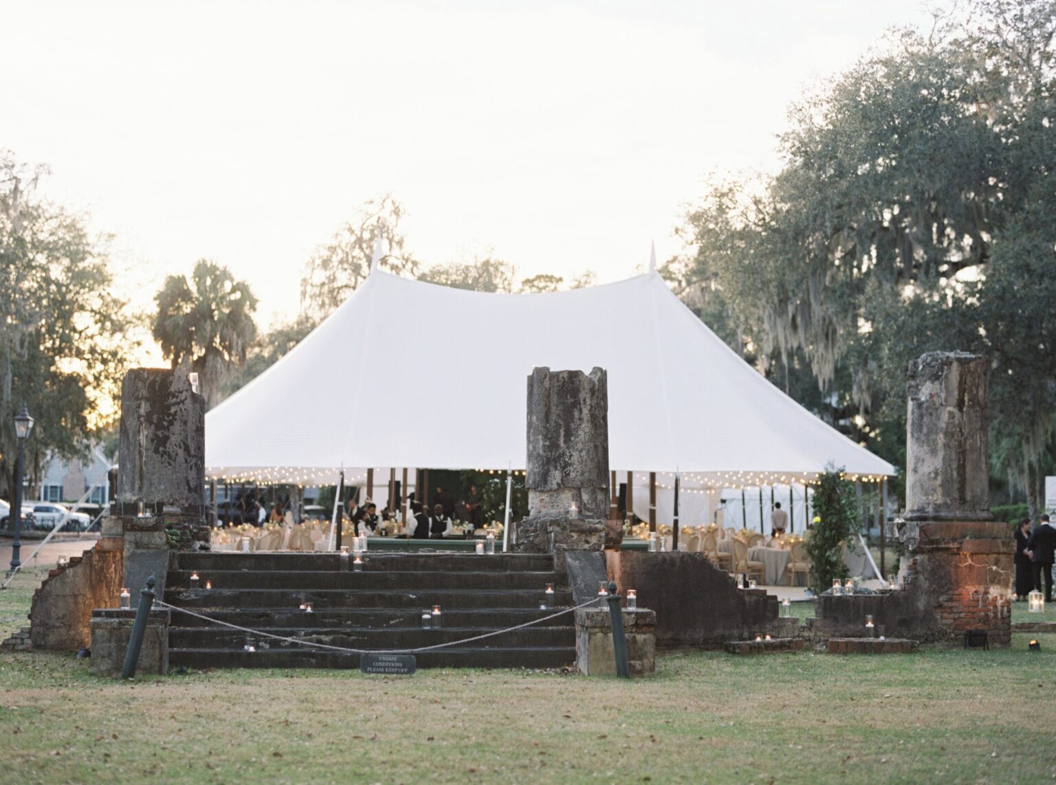 A white tent among live oaks and ruins at Palmetto Bluff