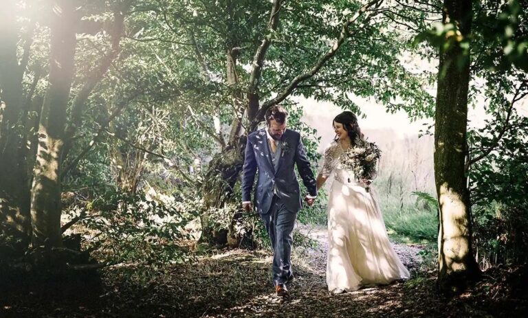 The couple walking hand in hand through the woodland in the grounds, Broadoaks Country House