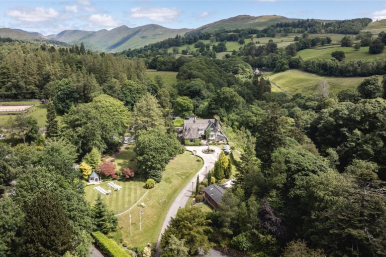 An aerial of the house in its wooded grounds with the Lakeland fells beyond, Broadoaks Country House