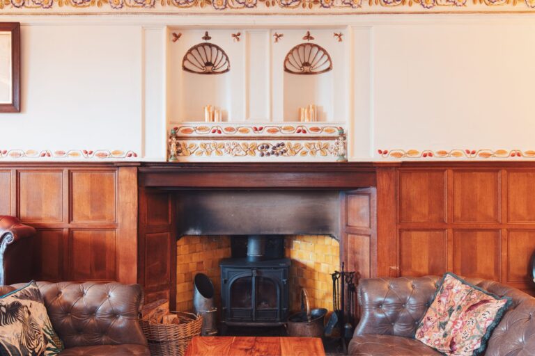 The Music Room fireplace, a wood-burner in an oak overmantel below the painted frieze and shell niches, Broadoaks Country House
