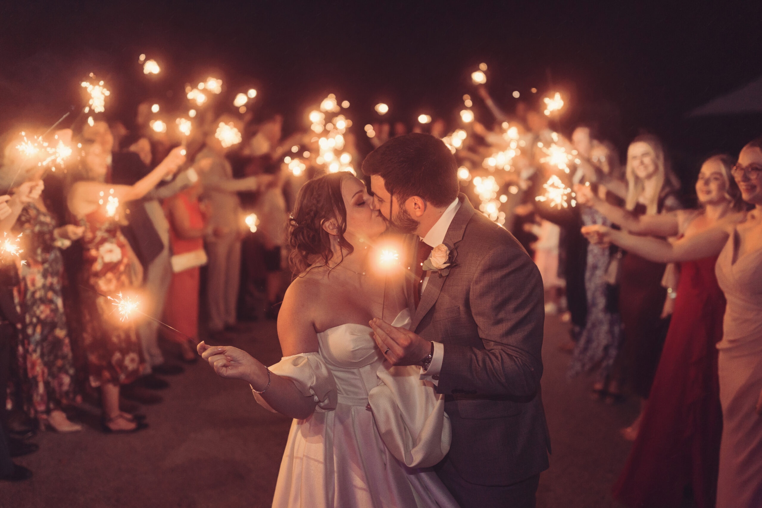 A sparkler tunnel, the couple kissing as guests hold sparklers overhead, Broadoaks Country House