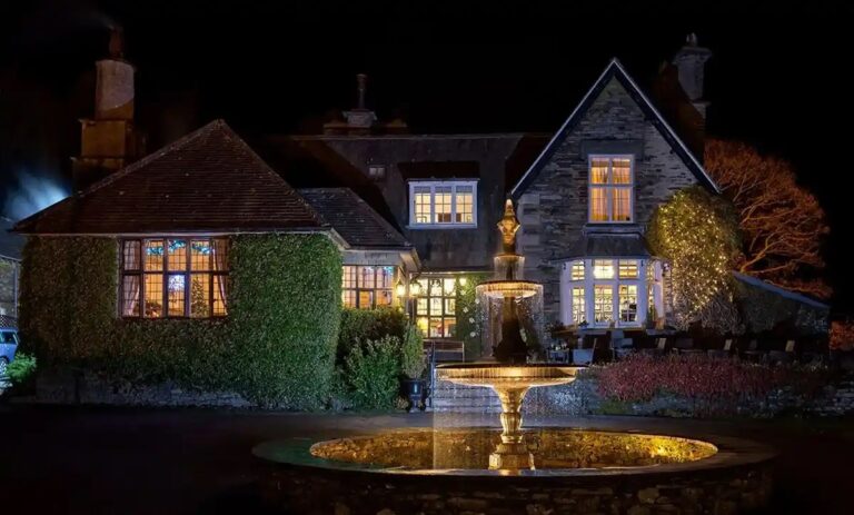 The house at night, the windows lit and the fountain floodlit, Broadoaks Country House