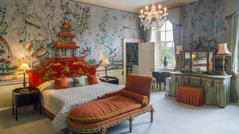 The Prince Regent Suite bedroom, with chinoiserie wallpaper, a pagoda-topped bed and a chaise at its foot, Brocket Hall