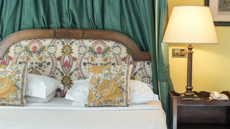 A padded floral headboard, green silk hangings and a bedside lamp in one of the estate's bedrooms, Brocket Hall
