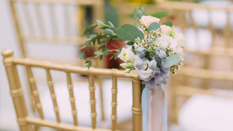A posy of white roses and blue hydrangea tied to a gold chair in the Oak Room, Brocket Hall