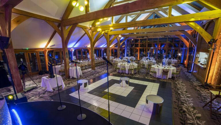 The Oak Room set for an evening reception, with a dance floor, band stand and round tables under the timber roof, Brocket Hall