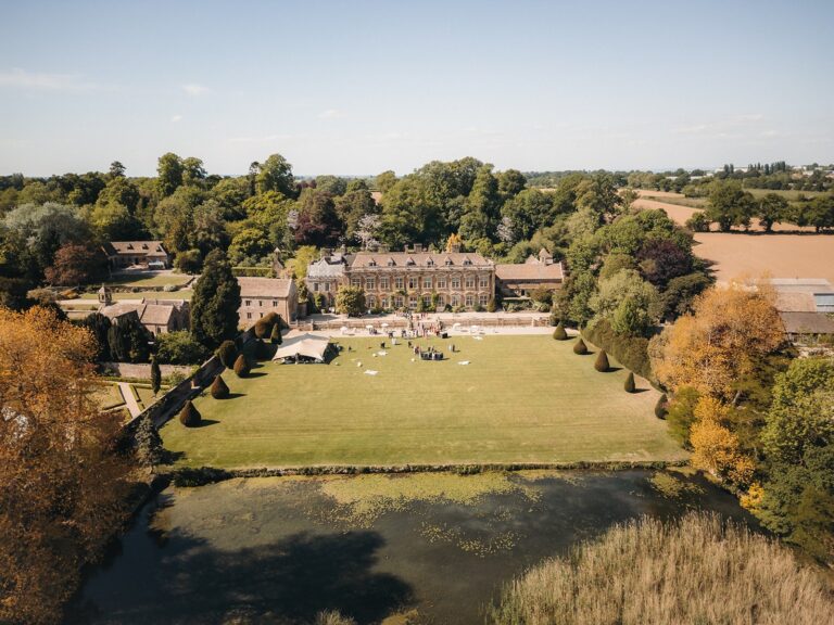 Aerial view over the lake and the long south lawn to the house, with the stables, church and Somerset farmland beyond, Brympton House