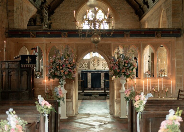 Inside St Andrew's Church, the carved screen and aisle dressed with pink and white flowers and candles, Brympton House