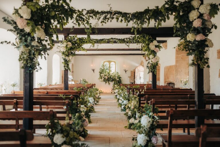 The Chapel dressed with green garlands and white roses along the beams and the aisle, Brympton House