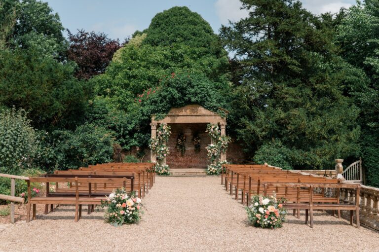 The gravel aisle and wooden benches leading to the Temple, with flower arrangements at the end of each row, Brympton House