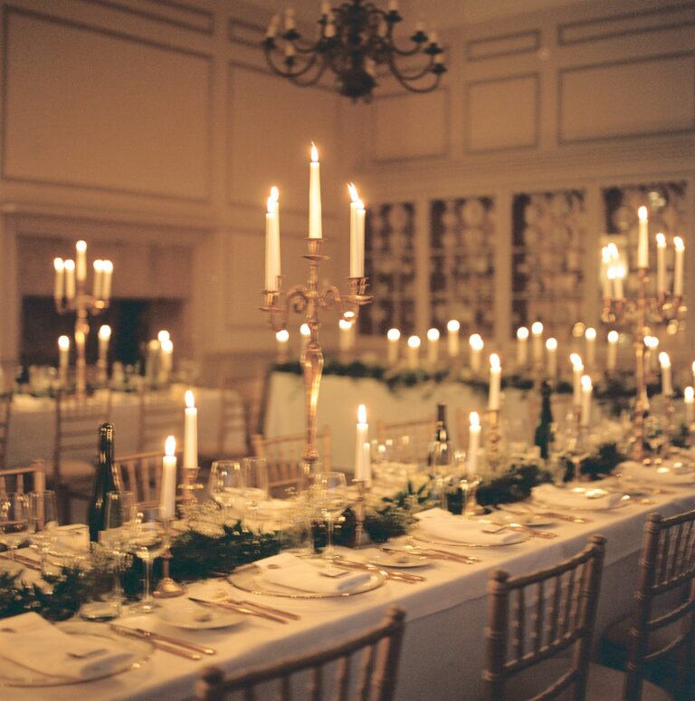 A long table lit by tall candles in silver candelabra, with greenery down the centre, Brympton House