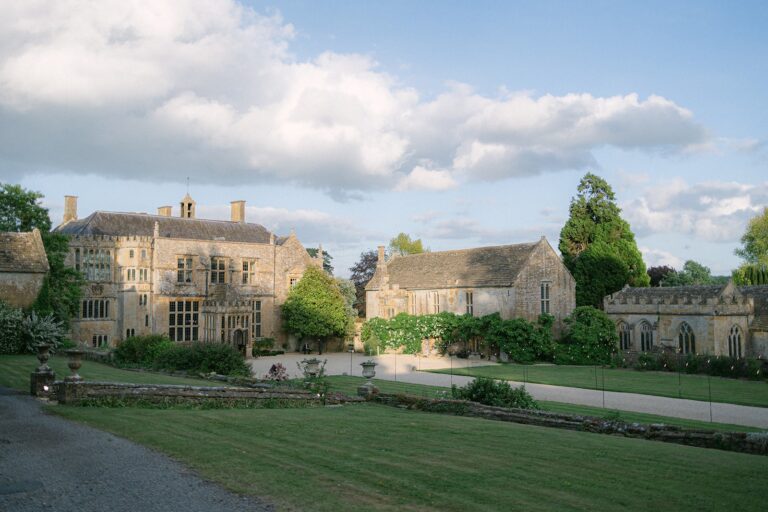 The gabled stone front of the house with its neighbouring ranges and the church across the lawn, Brympton House