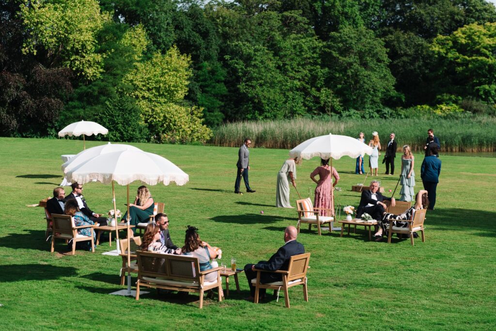 Garden furniture and white parasols set out on the lawn for a drinks reception, Brympton House