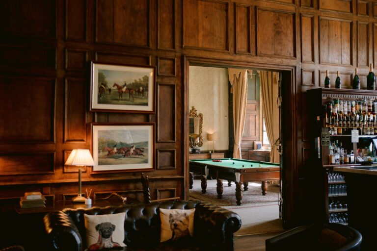 A wood-panelled bar room with leather sofas, racing prints and a full-size snooker table beyond, Brympton House