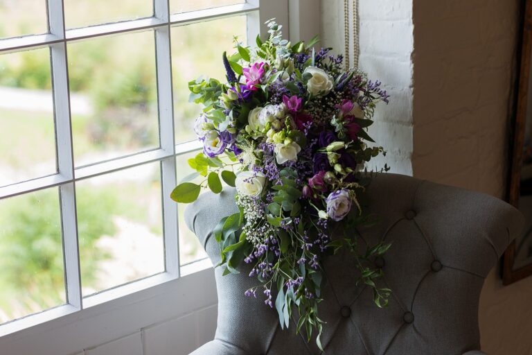 A bouquet of purple and white flowers resting on an armchair by a window, Bury Court