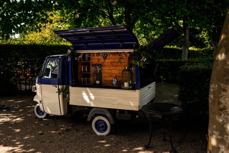 A small three-wheeled bar van under the trees in the garden, Bury Court