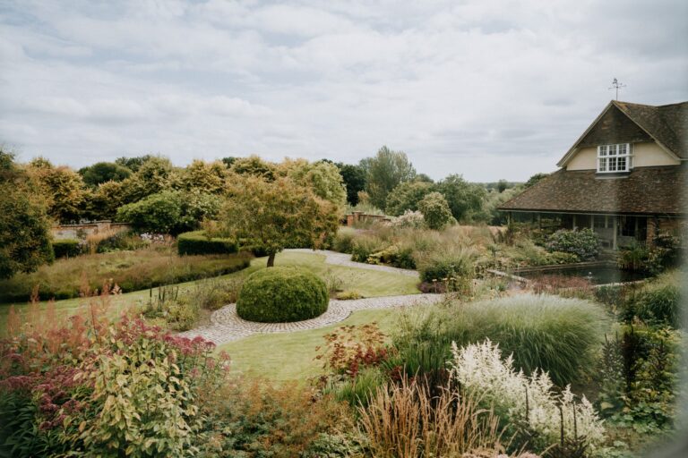 Grasses and perennials in the gardens, with the house roof behind, Bury Court