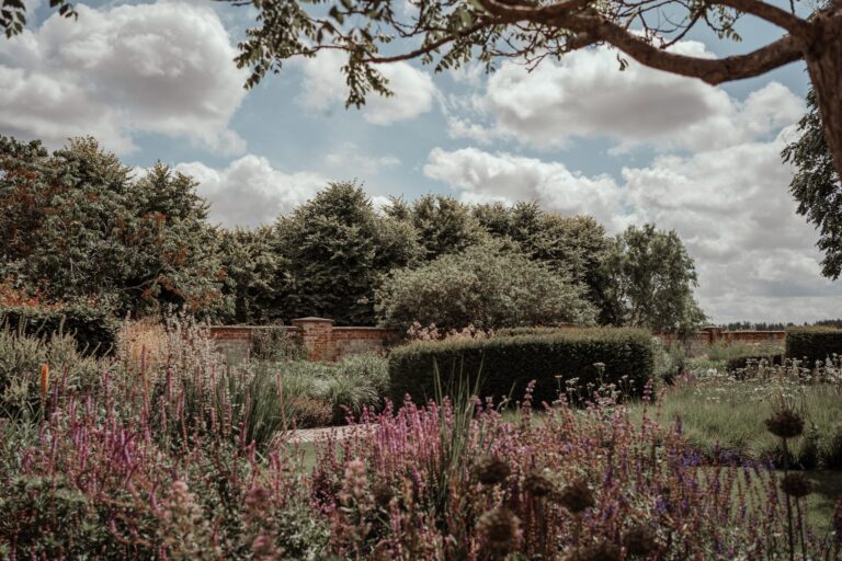 Pink and purple perennials inside the walled garden under a wide summer sky, Bury Court